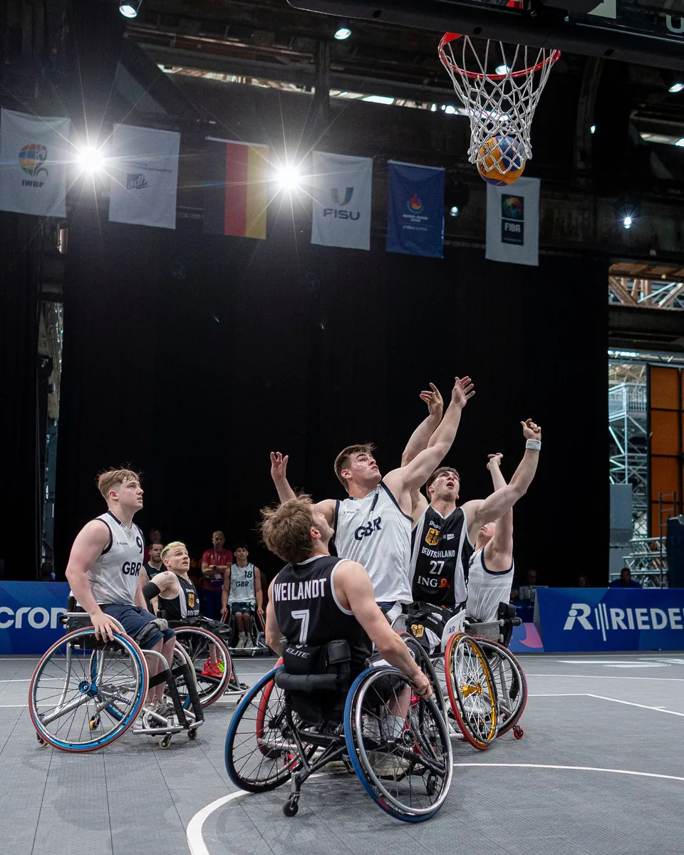Wheelchair basketball players reaching for the ball beneath the basket.